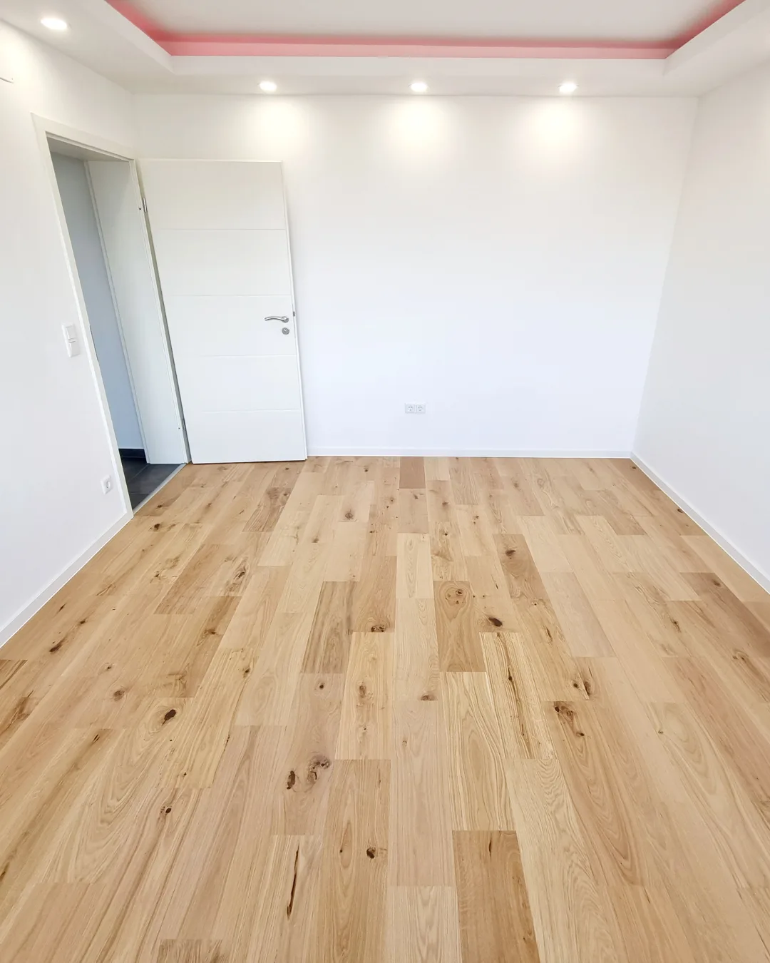 Renoviertes helles Zimmer mit neuem Holzboden, umgesetzt von Bauvia Concept